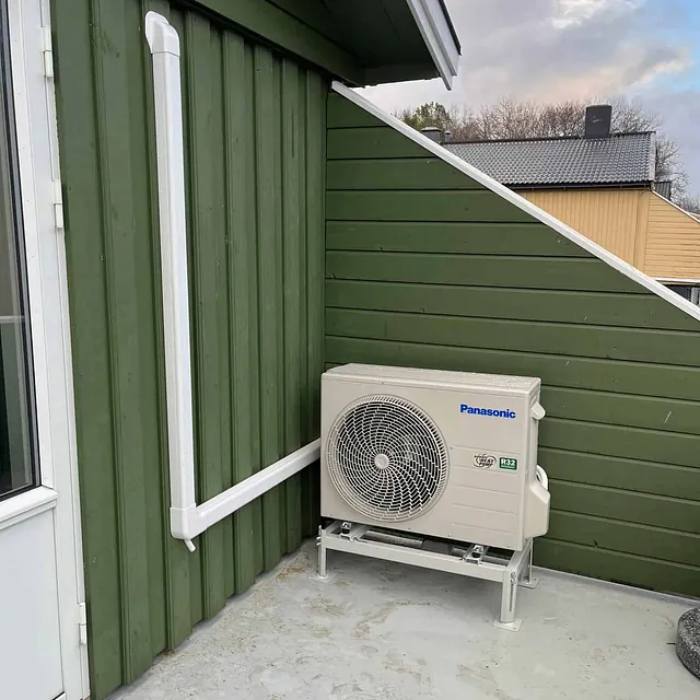 Panasonic utedel plassert på veranda utenfor grønnmalt hus med hvite karmer.